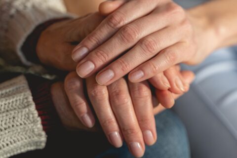 Healthcare worker holding hands with a patient, symbolizing care, trust, and support in a medical setting